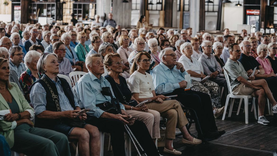 Die Besucher des Gottesdienstes sitzen auf weißen Stühlen.