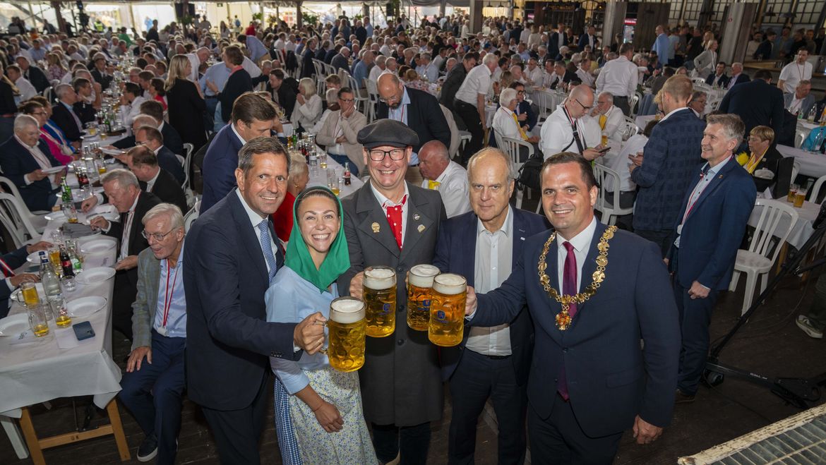 Die in der Bildunterschrift genannten Personen halten große Biergläser in der gut gefüllten Niedersachsenhalle